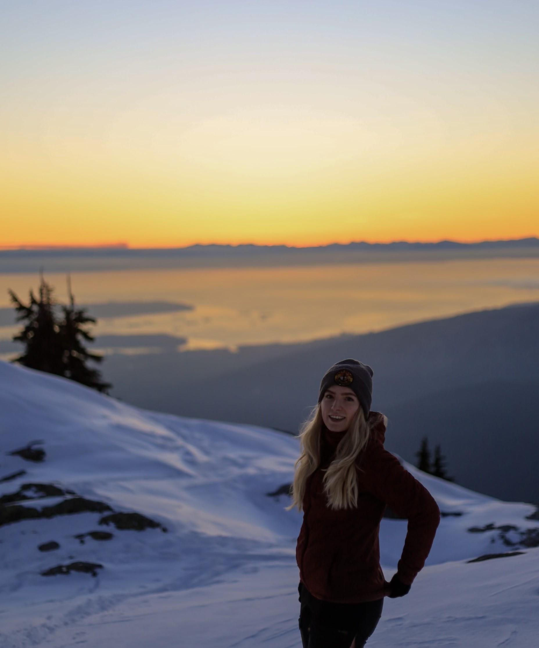 women snow trekking with ocean, mountain views and sunset in the background